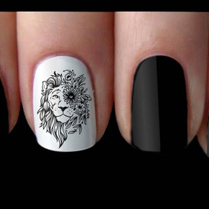 May include: Close-up of a fingernail with a black and white lion design with flowers. The design is on a white background and the nail is surrounded by other black nails.