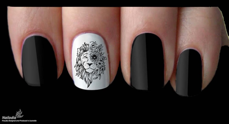 May include: Close-up of a fingernail with a black and white lion design with flowers. The design is on a white background and the nail is surrounded by other black nails.