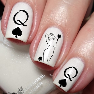 May include: White nail polish with black nail art featuring the Queen of Spades playing card. The nail art includes a stylized image of a woman and the letter Q.