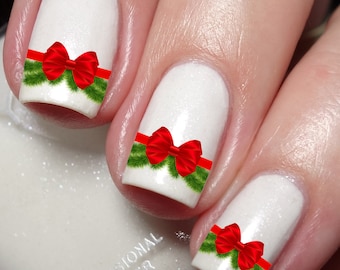 May include: White nails with a Christmas-themed design. Each nail has a green garland with a red bow on top.