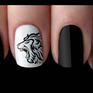 May include: Black and white nail art decals featuring a roaring lion head design. The decals are applied to a white nail polish base with the remaining nails painted black.