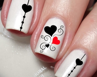 May include: White nail polish with black and red heart nail art designs. The nail art features black hearts, red hearts, and black swirls.