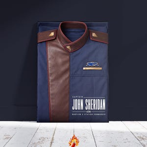 May include: A navy blue uniform jacket featuring brown leather-like shoulder panels, a high collar, and gold-tone accents. The chest displays a blue and gold emblem. Text reads: CAPTAIN JOHN SHERIDAN BABYLON 5 STATION COMMANDER.