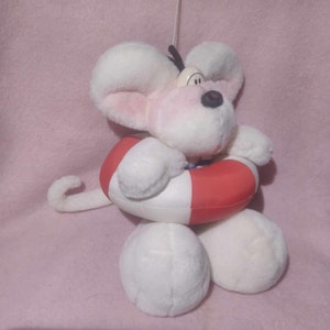 Könnte beinhalten: Ein weißes Stoffmaus-Spielzeug mit großen Ohren, einer schwarzen Nase und einer rot-weißen Schwimmweste um die Mitte. Die Maus hat einen langen, gebogenen Schwanz, vor einem rosa Hintergrund.