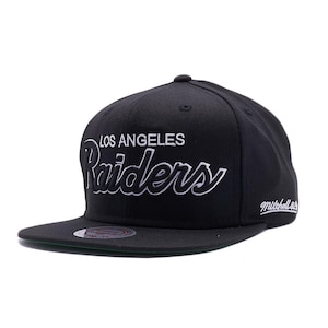 May include: A black Los Angeles Raiders baseball cap with a flat brim. The team name is embroidered in white script across the front. The cap has a green underside and a Mitchell & Ness logo.