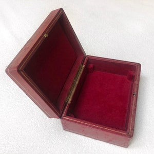 May include: A red velvet lined box with a gold trim. The box is open and empty.