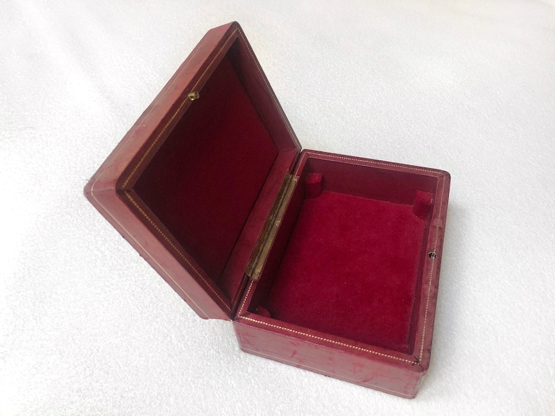 May include: A red velvet lined box with a gold trim. The box is open and empty.