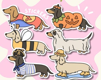 Könnte beinhalten: Eine Sammlung von sechs Dackel-Aufklebern mit dem Text TheValleyCo und STICKERS. Die Hunde tragen verschiedene Kostüme, darunter einen Superhelden, einen Kürbis, eine Biene, ein Gespenst, einen Piraten und einen Hund mit Regenhut und Stiefeln.