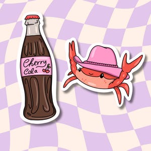 May include: A sticker featuring a cartoon illustration of a red crab wearing a pink cowboy hat and a brown glass bottle with a white label that says "Cherry Cola".