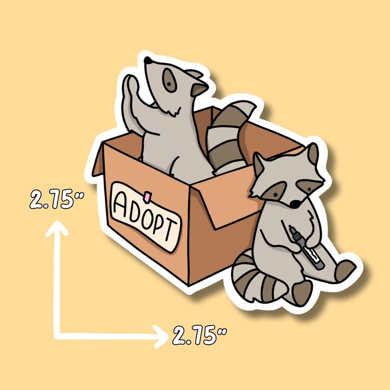 May include: A sticker of two raccoons in a cardboard box with the word "ADOPT" written on the side. The box is 2.75 inches wide and 2.75 inches tall.