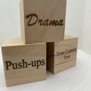 May include: Three wooden blocks with different text engraved on each. The top block says "Drama", the middle block says "Push-ups", and the bottom block says "Your Custom Text".