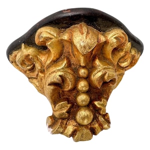 Peut inclure: Applique de meuble orné de style ancien, avec une finition dorée et un dessus marron foncé. Le design comprend des motifs floraux et des volutes détaillés, avec une série de petites sphères au centre. Idéal pour ajouter une touche vintage aux meubles.