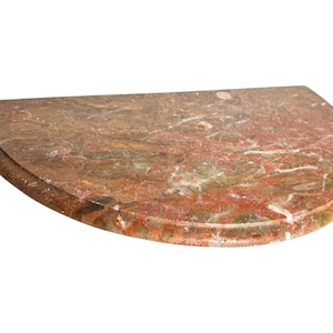 Puede incluir: Un estante semicircular hecho de mármol pulido rojo y marrón con vetas blancas. La pieza presenta un borde frontal redondeado y suave y un borde posterior plano, mostrando el patrón de piedra natural con un acabado brillante en la superficie.