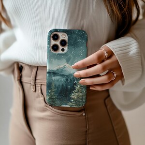 Phone case with watercolor snowy mountain forest scene at night in teal and green tones, aesthetic winter holiday gift for her