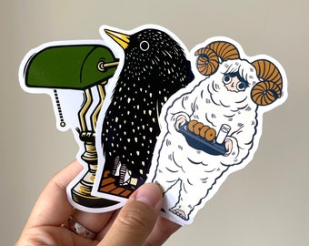 May include: Three stickers featuring a black and white bird, a white sheep with horns, and a green lamp. The sheep is holding a tray with a few small brown pastries and a small white cup.