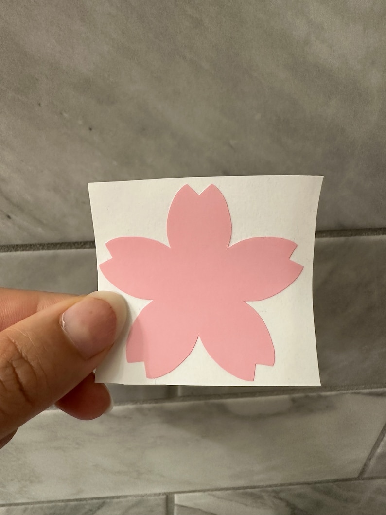 May include: A pink vinyl sticker of a cherry blossom flower.