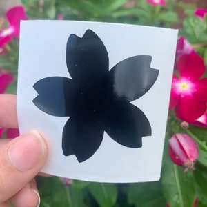May include: A black vinyl sticker with a cherry blossom design. The sticker is on a white background.