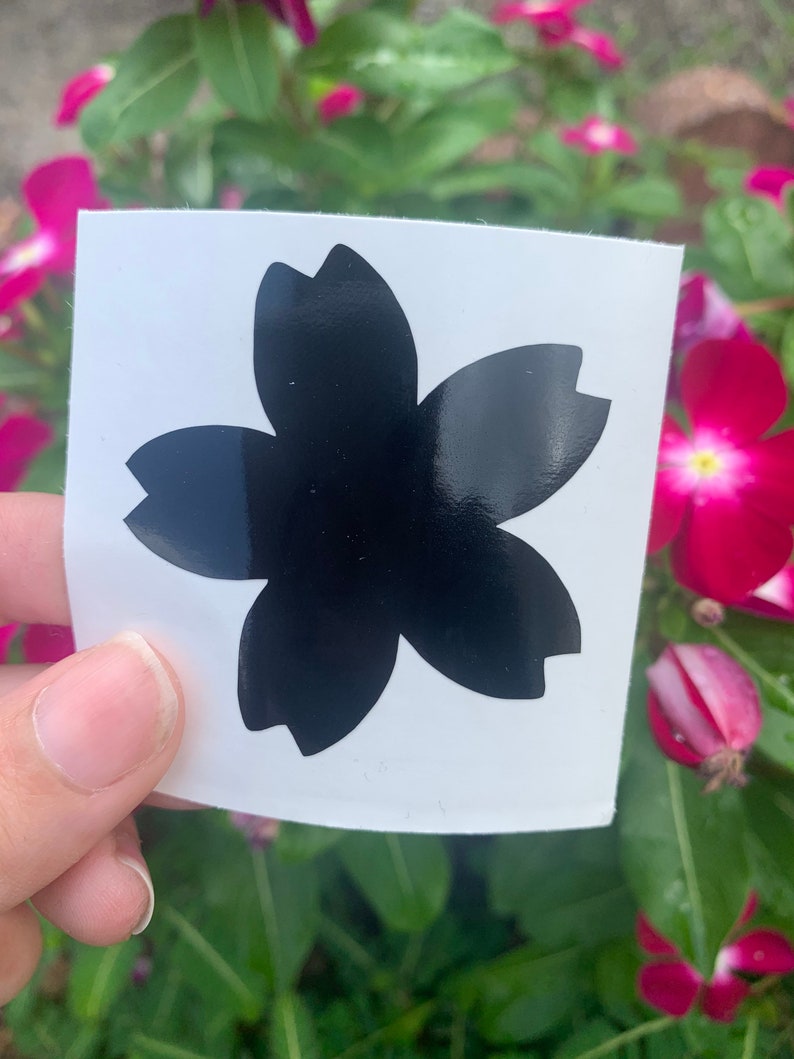 May include: A black vinyl sticker with a cherry blossom design. The sticker is on a white background.