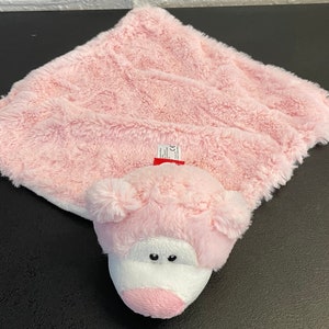 May include: Pink plush blanket with a pink pig head attached. The pig has white eyes and a pink nose.