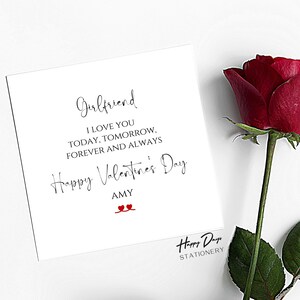May include: A white card with black text that reads "Girlfriend I love you today, tomorrow, forever and always Happy Valentine's Day Amy" with two red hearts. The card is next to a red rose.