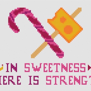 May include: Cross-stitch design featuring a candy cane and a cheese-shaped hammer crossed over each other. The text "IN SWEETNESS THERE IS STRENGTH" is displayed in pink and purple. A crown and candy icon are also included.