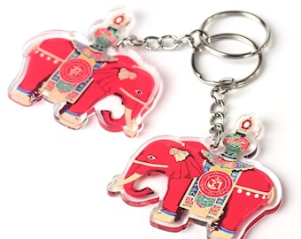 May include: Two red acrylic elephant keychains with a silver chain. Each elephant has a colorful design and a small crown on its head.