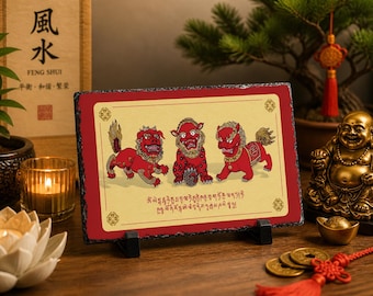May include: A decorative slate featuring three red Foo Dogs with gold accents on a cream background. The slate is displayed on a black stand, with a red border. The image includes text in a foreign language.