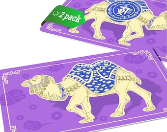 May include: Two purple cards with a gold and white camel illustration. The camel is wearing a blue and gold patterned saddle. The cards have a white border and a repeating pattern of clouds. The text "2 pack" is on a green tag.