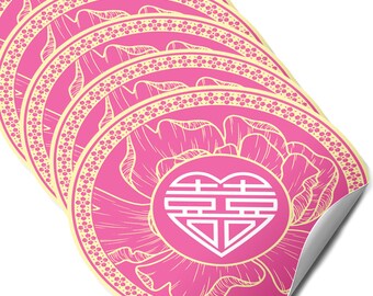 May include: A stack of pink, round stickers with a floral design and a heart-shaped symbol in the center. The stickers have a cream-colored border with a dotted pattern. The heart symbol is white.