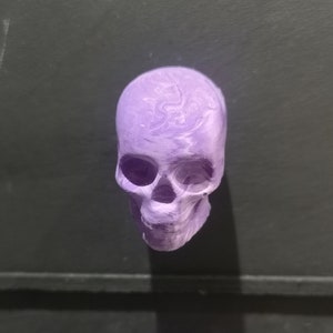 Peut inclure: Un objet en forme de crâne de couleur violette avec un motif marbré. Le crâne est fait d'un matériau lisse et dur et a une apparence réaliste.