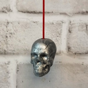 May include: A silver skull-shaped light pull with a red cord.