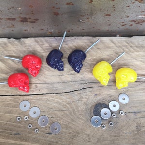 Peut inclure: Six poignées de tiroir en forme de crâne en rouge, jaune et violet avec des vis et des rondelles argentées.