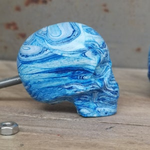 May include: Blue and white marbled skull shaped cabinet knob with a silver screw.