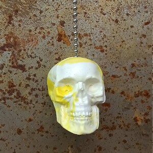 May include: A white and yellow skull-shaped light pull with a silver chain.