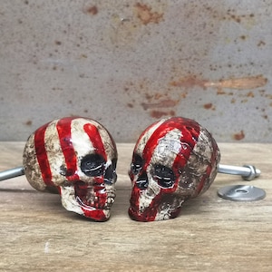 May include: Two red and white striped skull-shaped cabinet knobs with a silver screw.