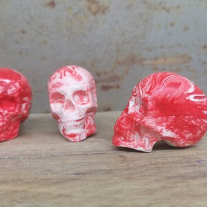 May include: Three red and white skull-shaped drawer pulls with a marbled effect.