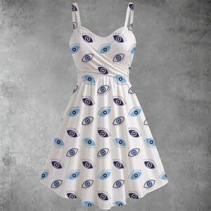 May include: White sundress with a blue eye print. The dress features a wrap-style bodice, spaghetti straps, and a flared skirt. The eye pattern is repeated across the entire dress, creating a unique and eye-catching design.