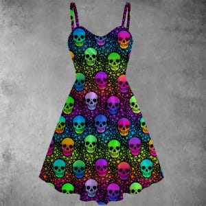 May include: A sleeveless dress with a black background covered in colorful skulls and stars. The skulls are in shades of green, yellow, orange, pink, purple, and blue. The dress has thin straps and a fitted bodice that flares out at the waist.