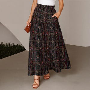 May include: A floor-length skirt featuring a dark plaid pattern with intricate botanical and mushroom motifs. The skirt has a high, gathered elastic waistband with a drawstring tie and side pockets, falling in a loose, flowing silhouette.