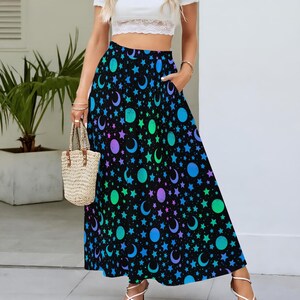 May include: A long black skirt featuring a celestial pattern of stars, moons, and planets in shades of blue, green, and purple. The skirt has a high waist and pockets. The skirt is made of a lightweight fabric.