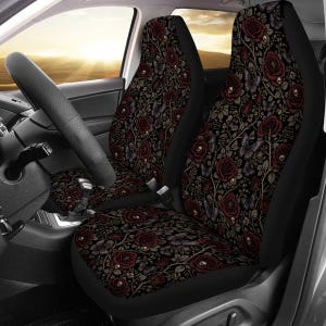 May include: A pair of car seat covers featuring a dark black background with a repeating pattern of deep red roses, small white skulls nestled within the floral stems, and purple butterflies. The fabric covers the entire front seat surface.