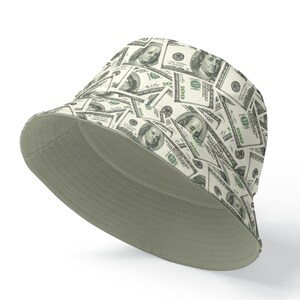 May include: A green and white bucket hat with a pattern of US dollar bills. The hat is made of a soft, comfortable material and has a wide brim.