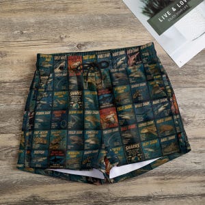 May include: Shorts featuring a grid pattern of various shark species illustrations, each labelled with its name. The design includes text such as Sharks Are Not The Enemy and includes a black drawstring at the elasticised waistband.