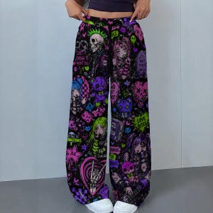 May include: Black wide-leg trousers with a vibrant, all-over print featuring skulls, anime-style characters, and various graphic elements in shades of pink, purple, green, and blue. Text includes phrases like "Cute Enough to Haunt You" and "Love Bites".