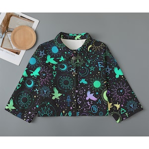 May include: A black cropped button-up shirt with a colorful celestial print featuring stars, moons, suns, and birds. The print also includes various symbols, including the zodiac signs.
