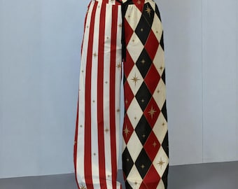 Peut inclure: Pantalon large présentant un design divisé avec des rayures verticales rouges et blanches d'un côté et un motif losange noir, rouge et crème de l'autre. Les deux côtés sont ornés de petites étoiles dorées et d'un cordon de serrage noir.