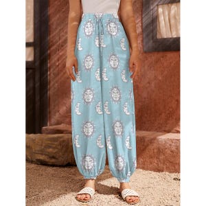 May include: Light blue wide-leg trousers with a white sun and moon print. The trousers have an elastic waistband with a drawstring.