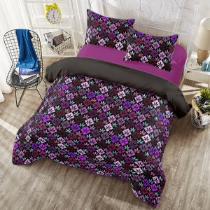 May include: A black and purple duvet cover with a repeating pattern of stylised cannabis leaves. The duvet cover is on a bed with two matching pillowcases.