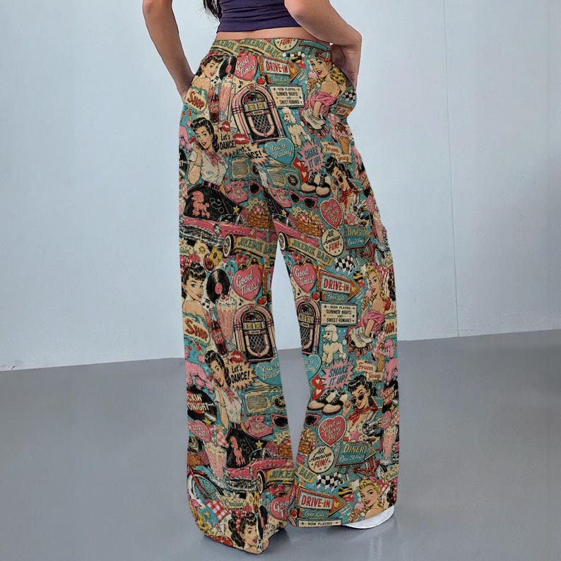 May include: Wide-leg pants featuring a colorful all-over print of 1950s-style illustrations, including jukeboxes, classic cars, diners, and pin-up figures. The pattern incorporates text such as Drive-In, Good Times, and Shake It Up on a teal background.