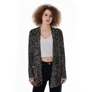 May include: A long-sleeved open-front cardigan featuring a dark black base with an intricate, repeating pattern of grey roses, small skulls, and butterflies. The garment has a straight hemline and a relaxed fit, showcasing a detailed botanical design.